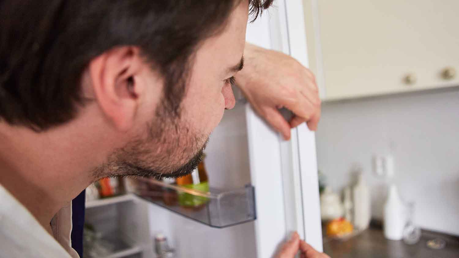 Man checking refrigerator door seal