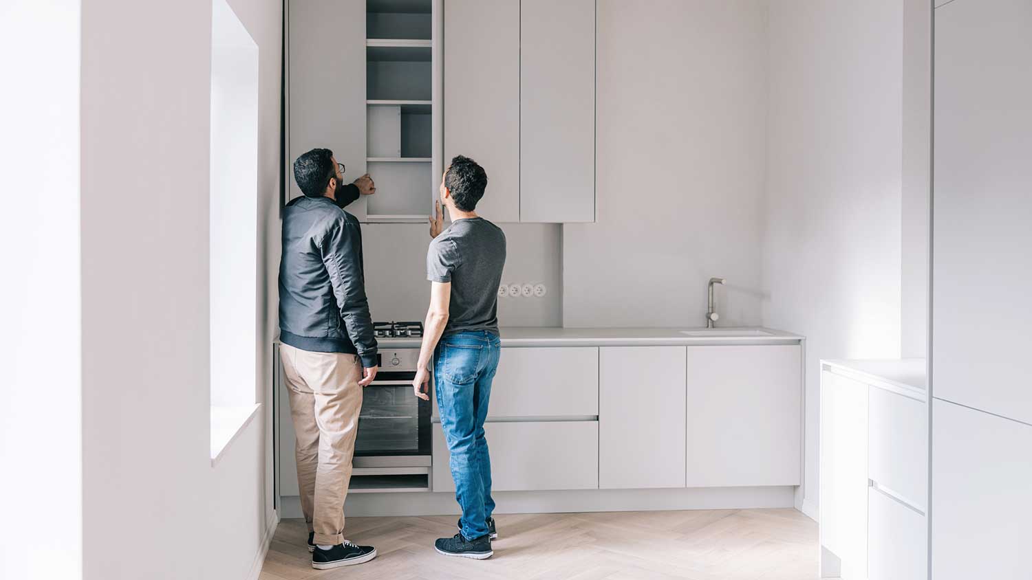 Couple checking kitchen cabinets of a new condo