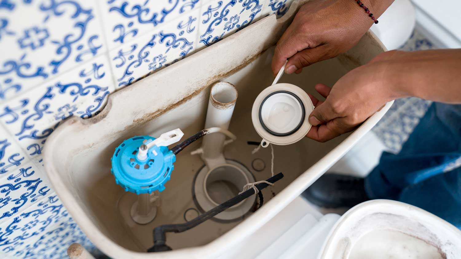 Closeup of a plumber checking toilet flapper