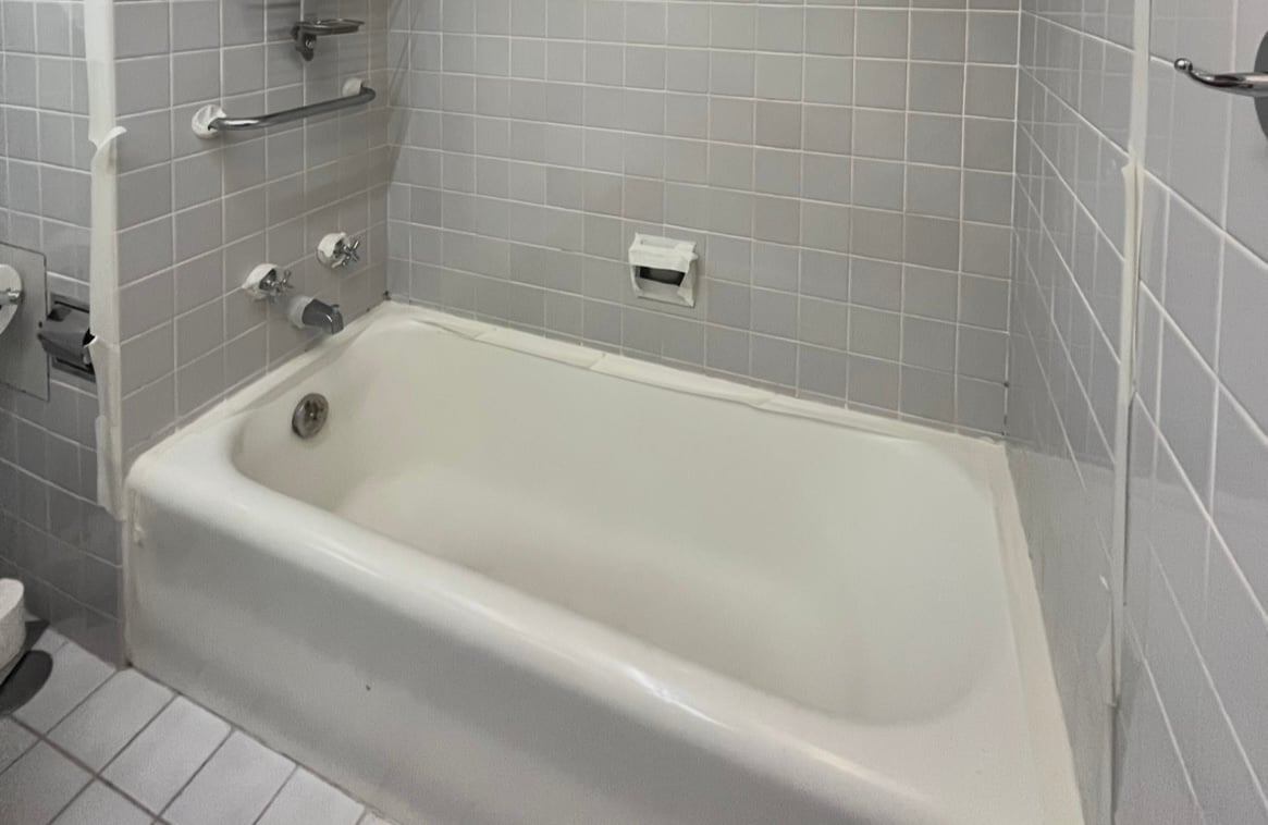 Outdated bathtub with gray tiles and white cast iron tub