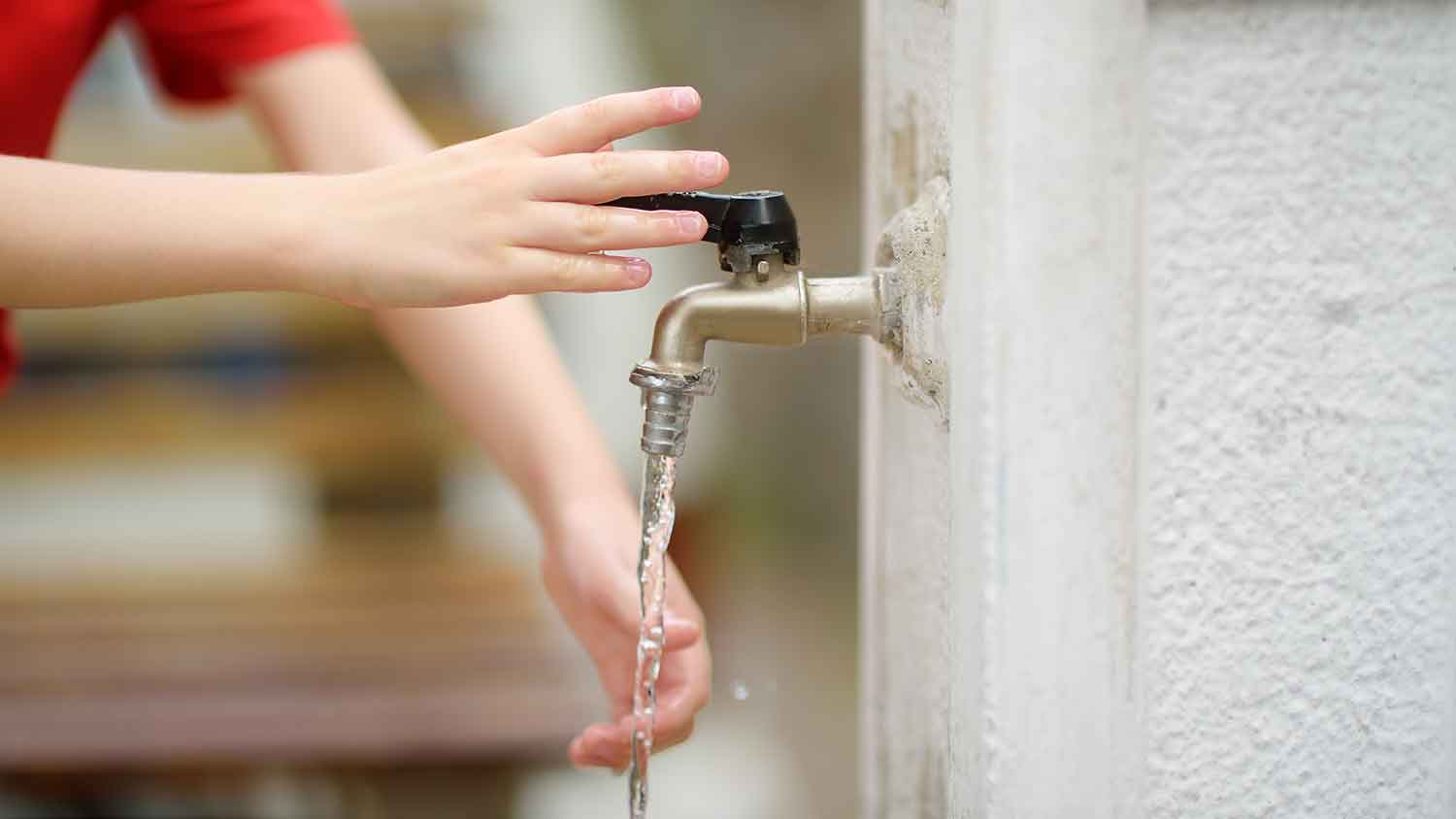 Child using ball valve faucet to wash hands