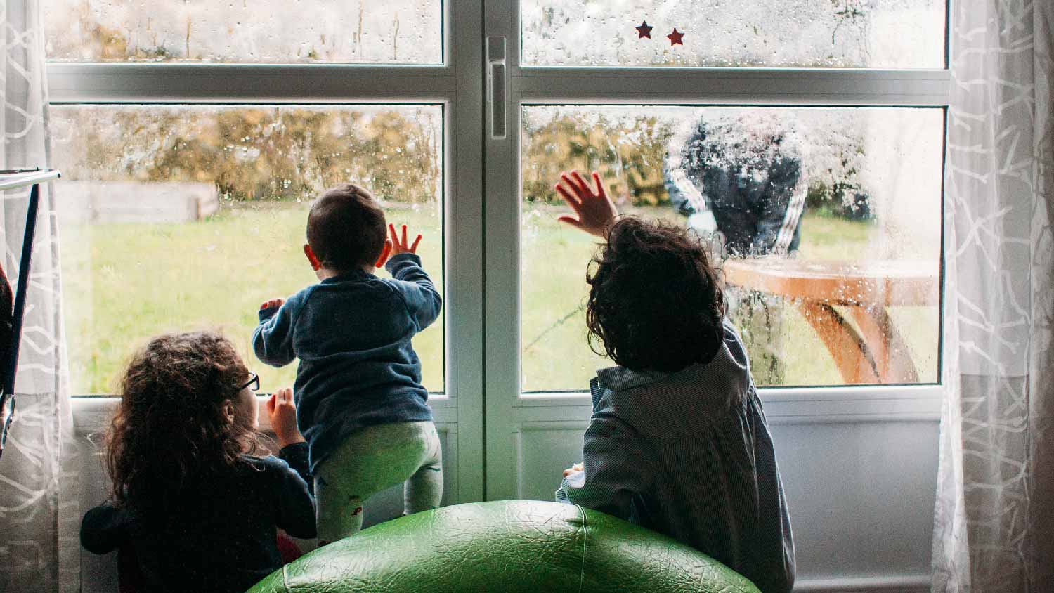 Three children looking out a foggy window