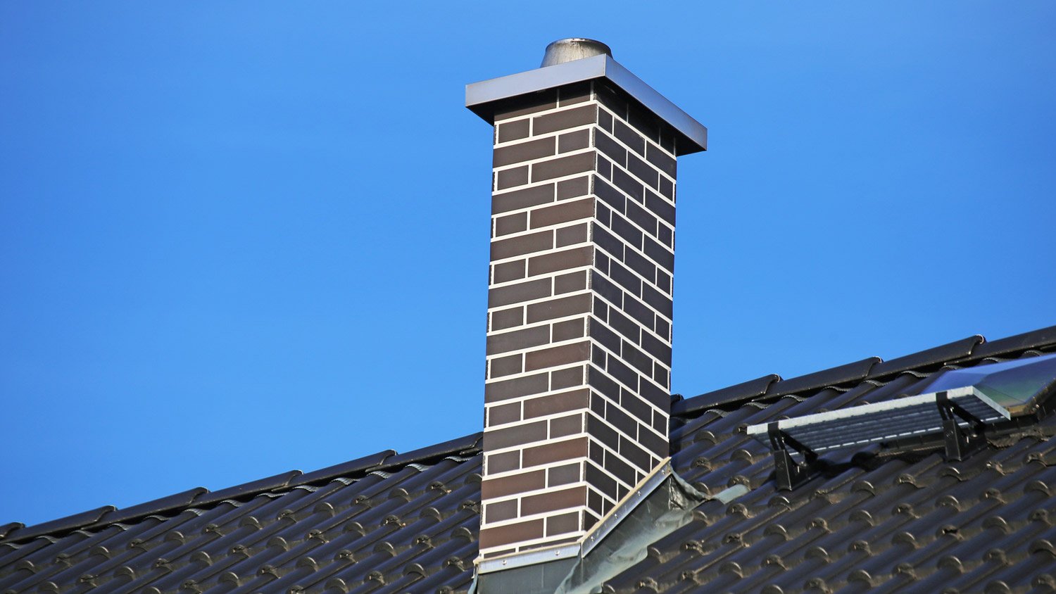 Chimney clad with clinker bricks on a newly covered roof