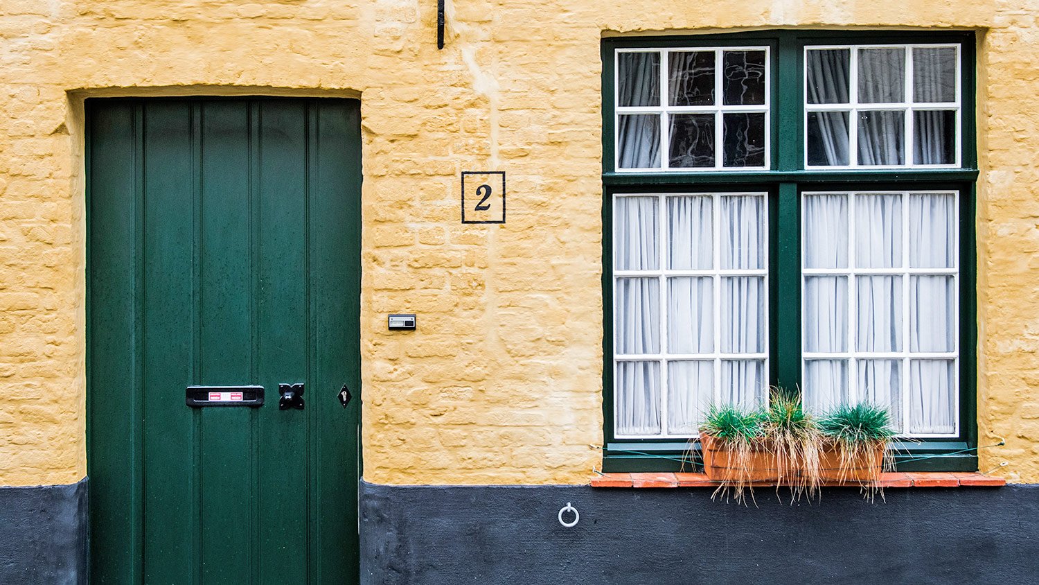 yellow-painted brick exterior with dark green front door 