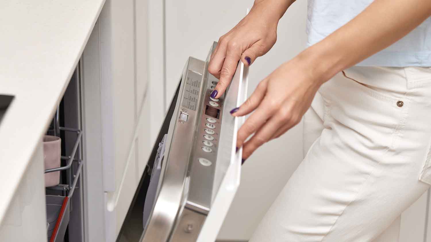 A person selecting a dishwasher cleaning cycle 