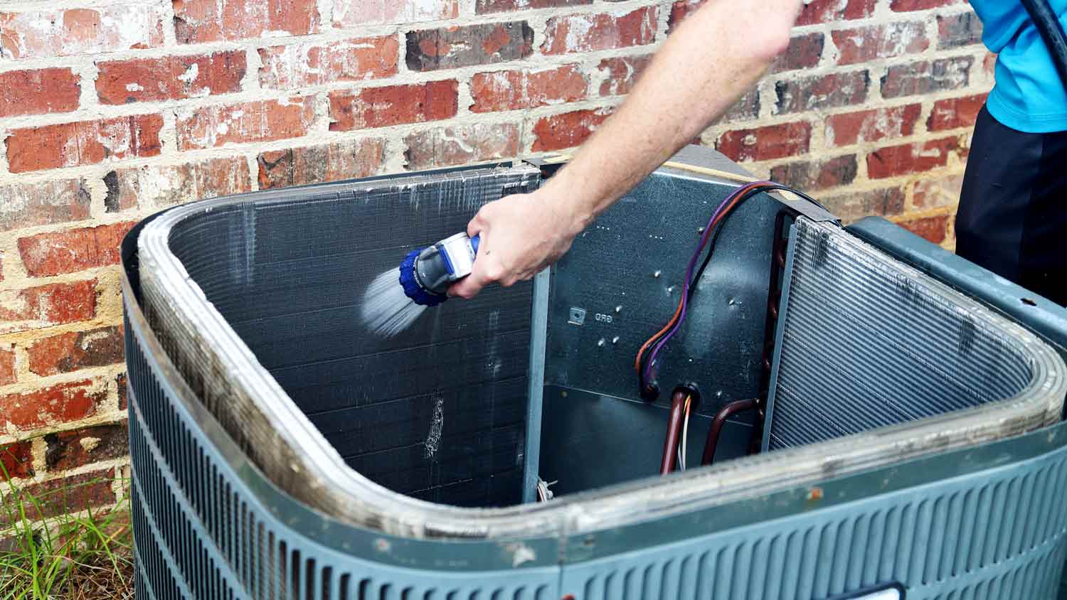 man cleaning air conditioner coils