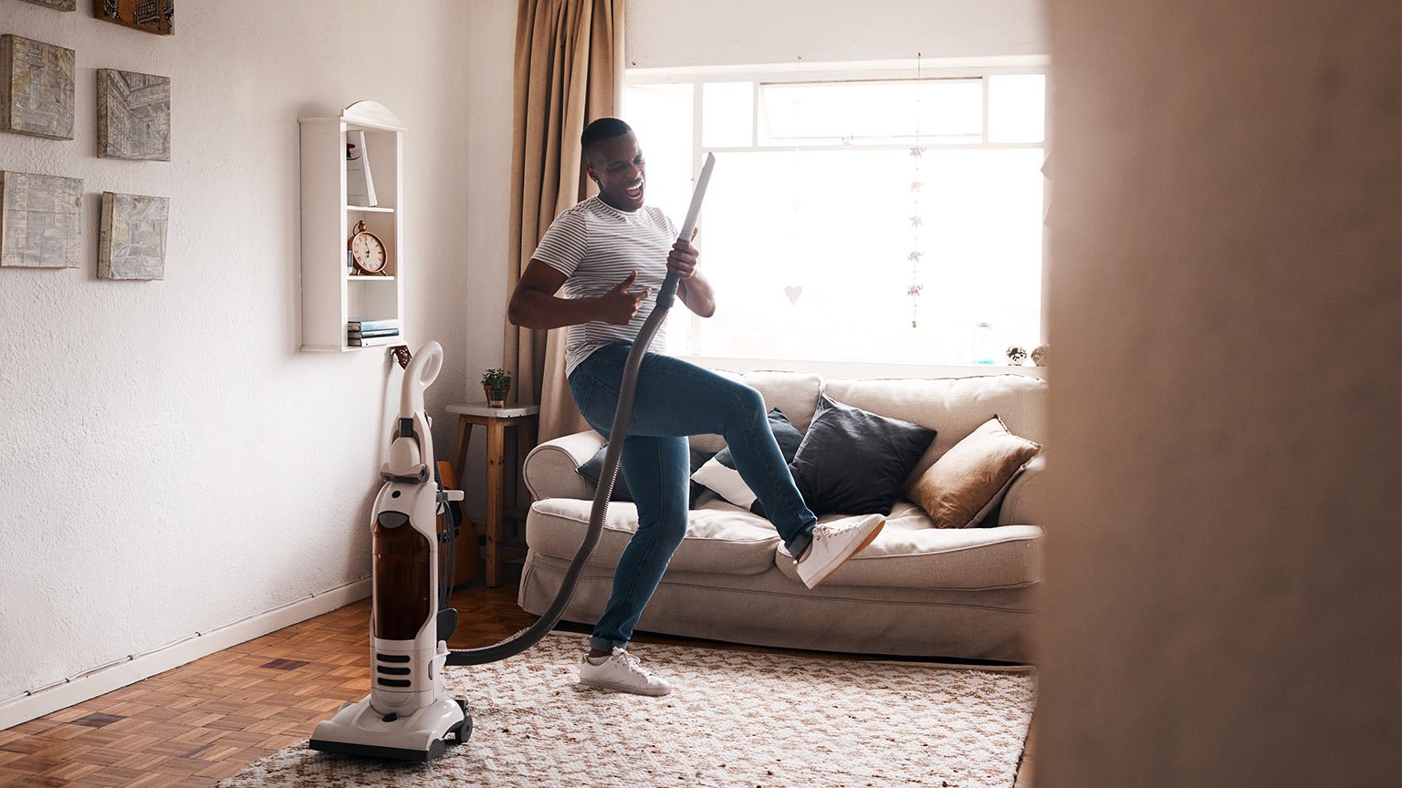 Shot of a young man dancing while busy vacuuming the living room