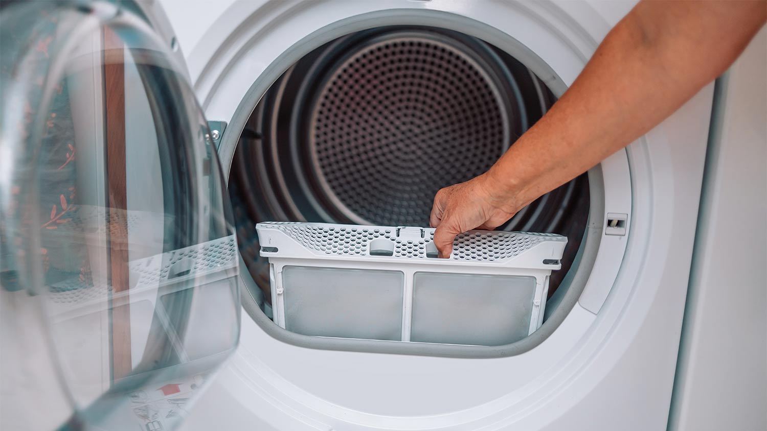 A person cleaning a dryer lint filter