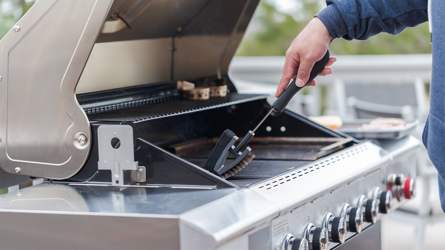 Tool cleaning large silver grill.