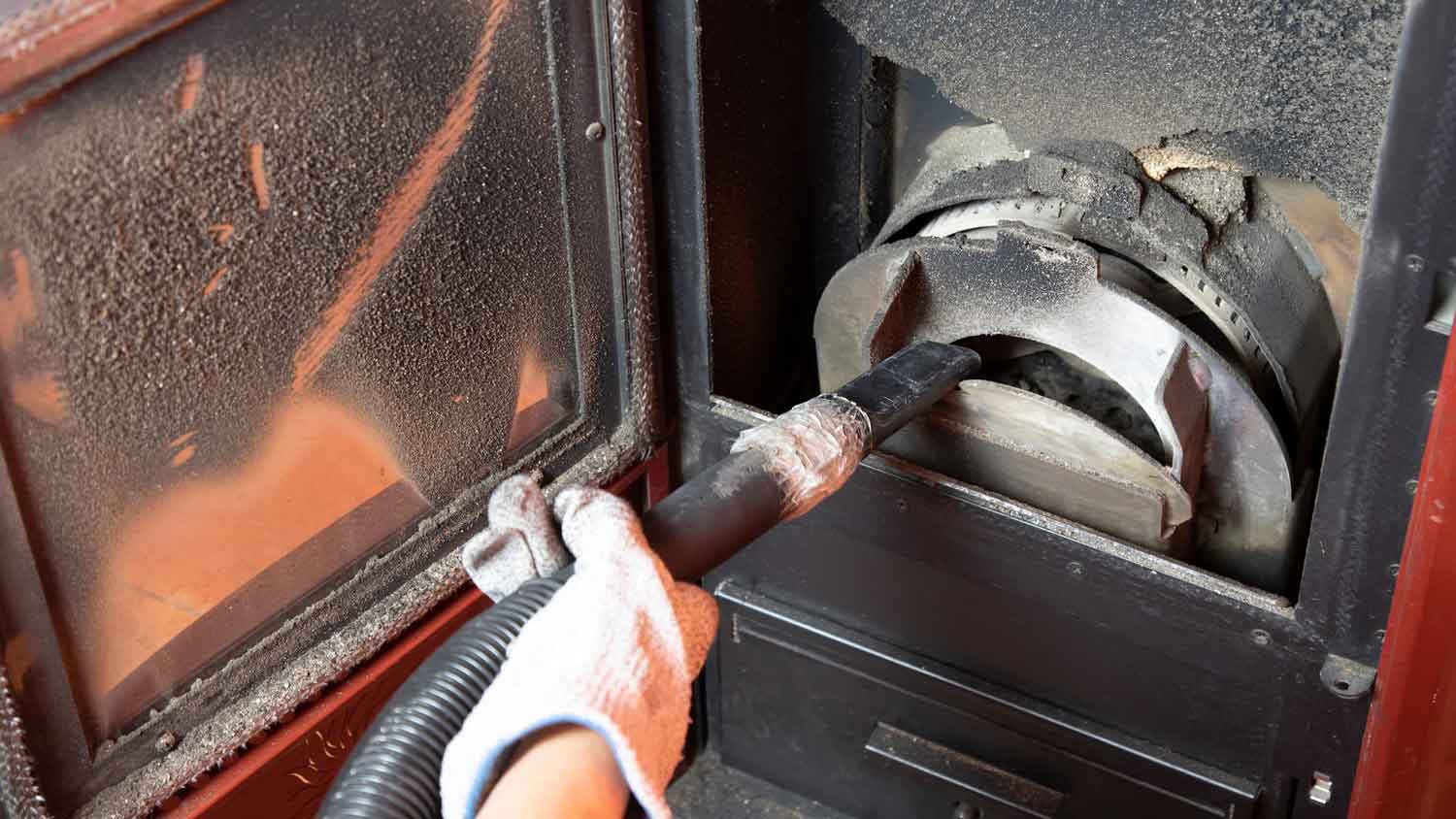 person cleaning pellet stove