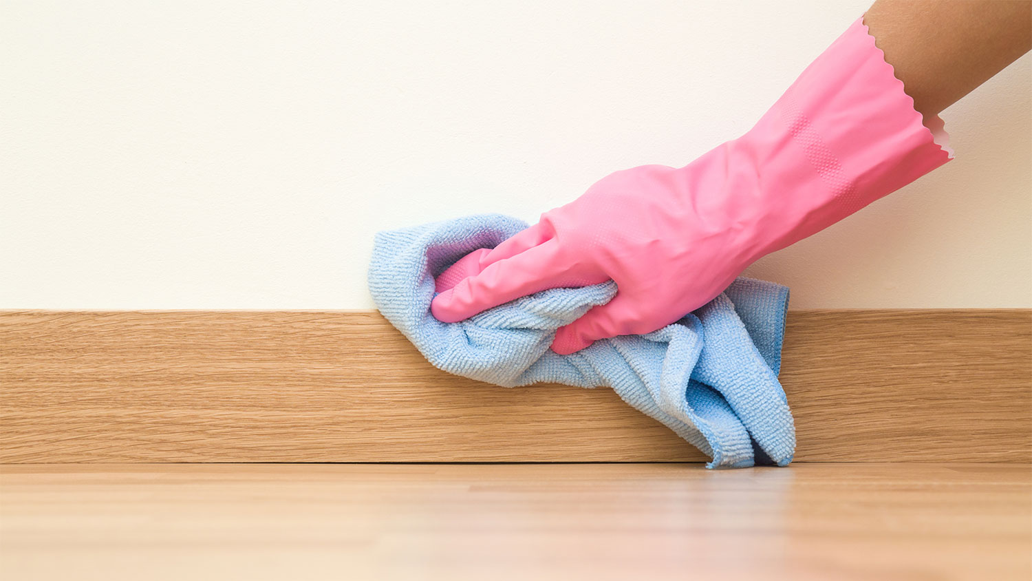 A closeup of a hand cleaning a baseboard