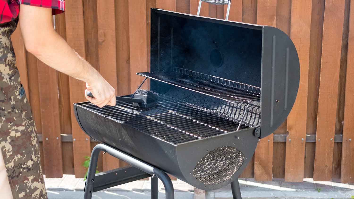 Using brush to clean charcoal grill