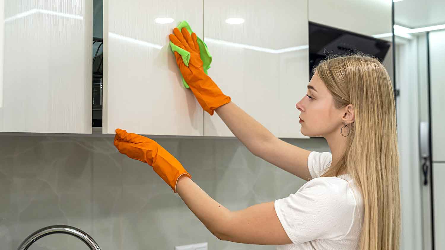 Woman using cloth to clean kitchen cabinets