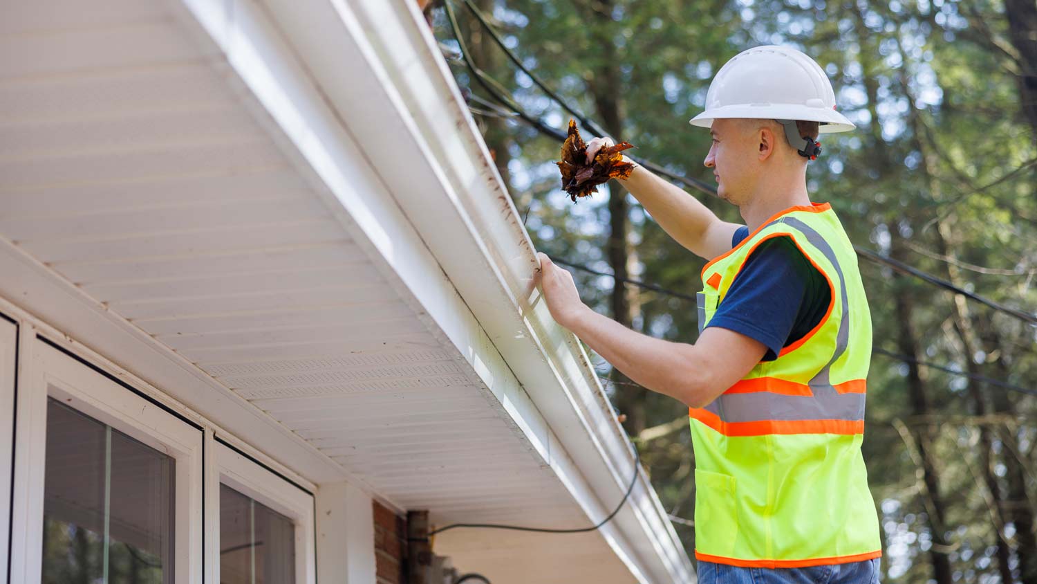 man cleaning leaves from gutter