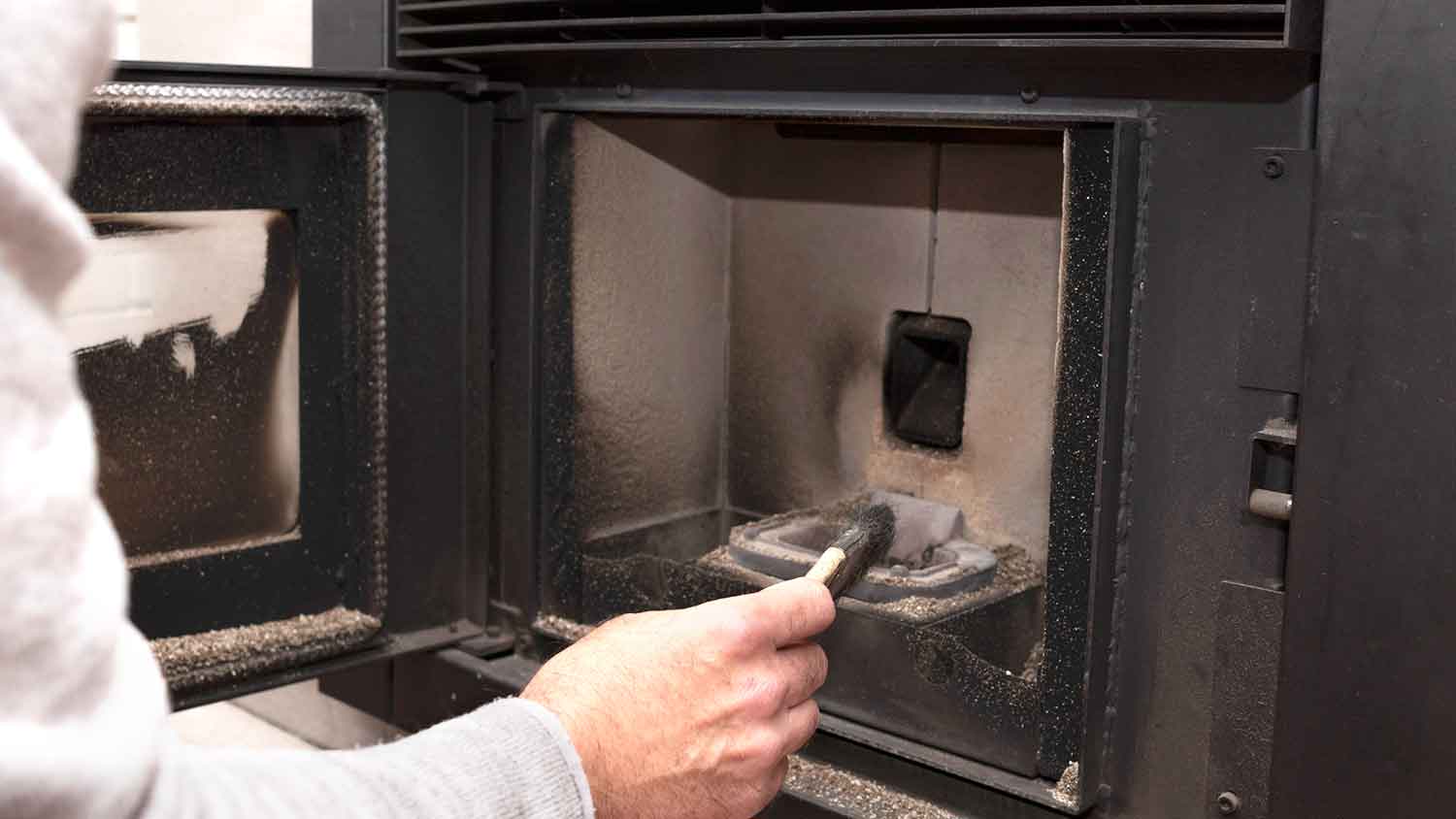 Man using brush to clean pellet stove interior