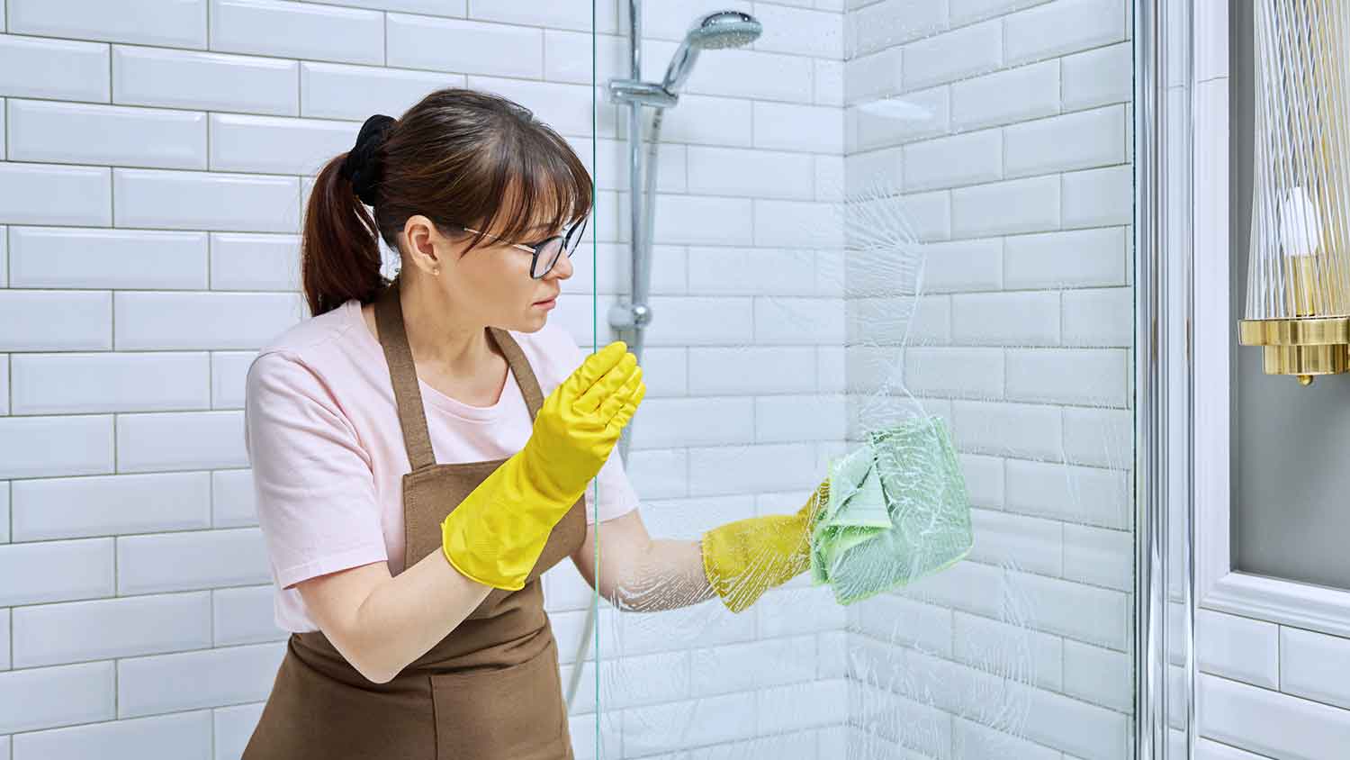 Woman cleaning shower glass door