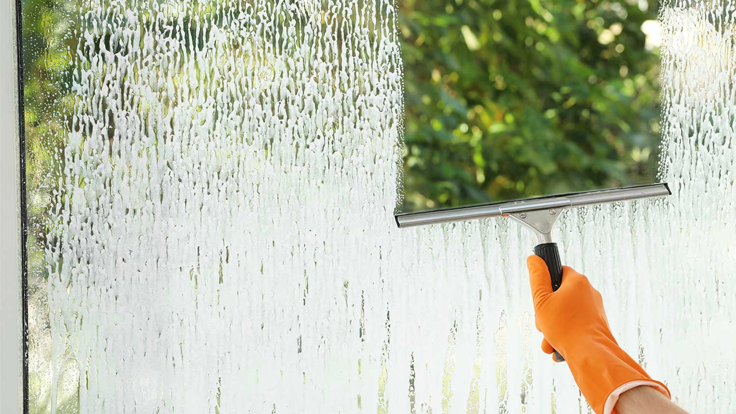 A man cleans a window with a squeegee