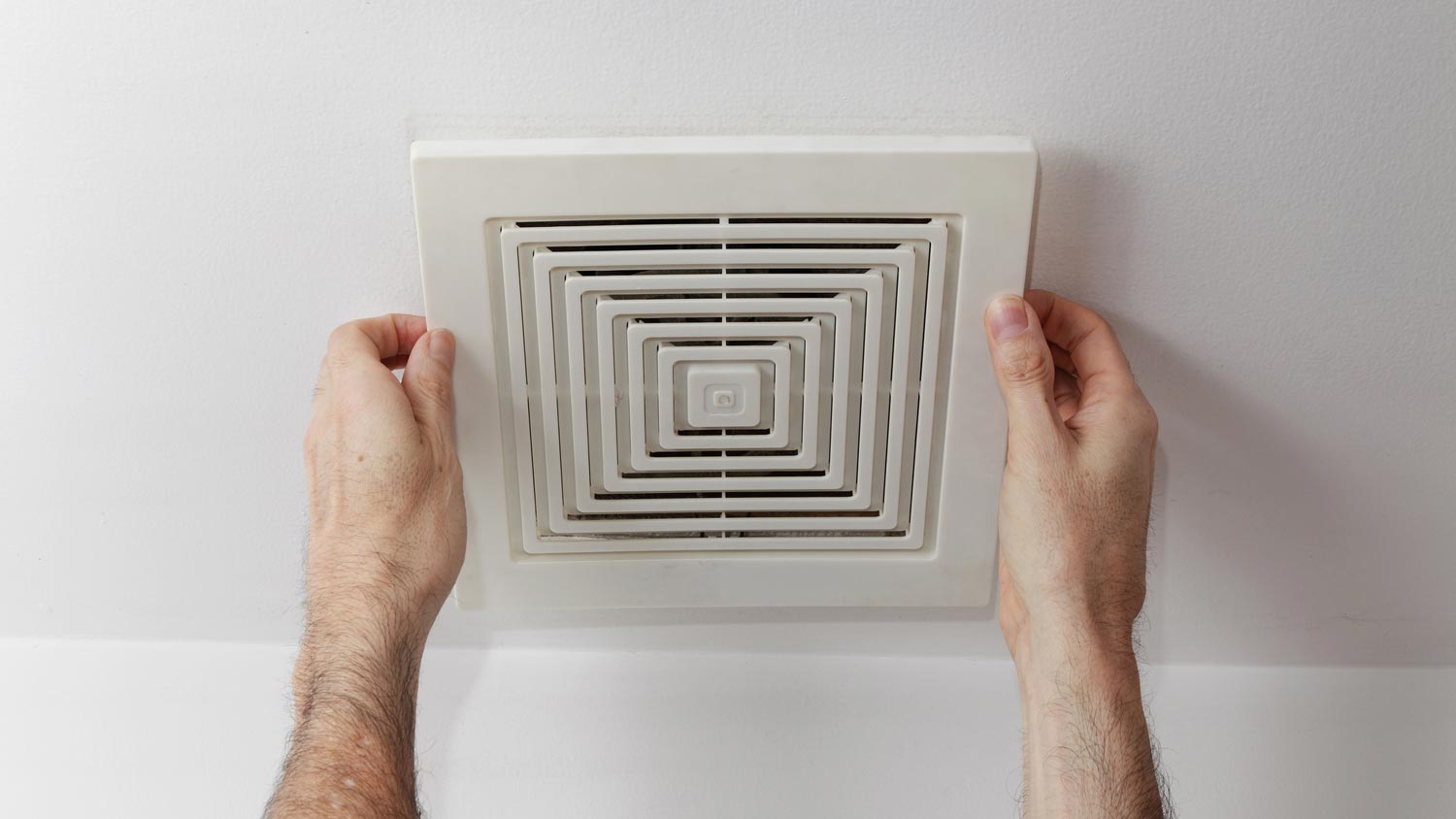 Close-up of man installing an exhaust fan