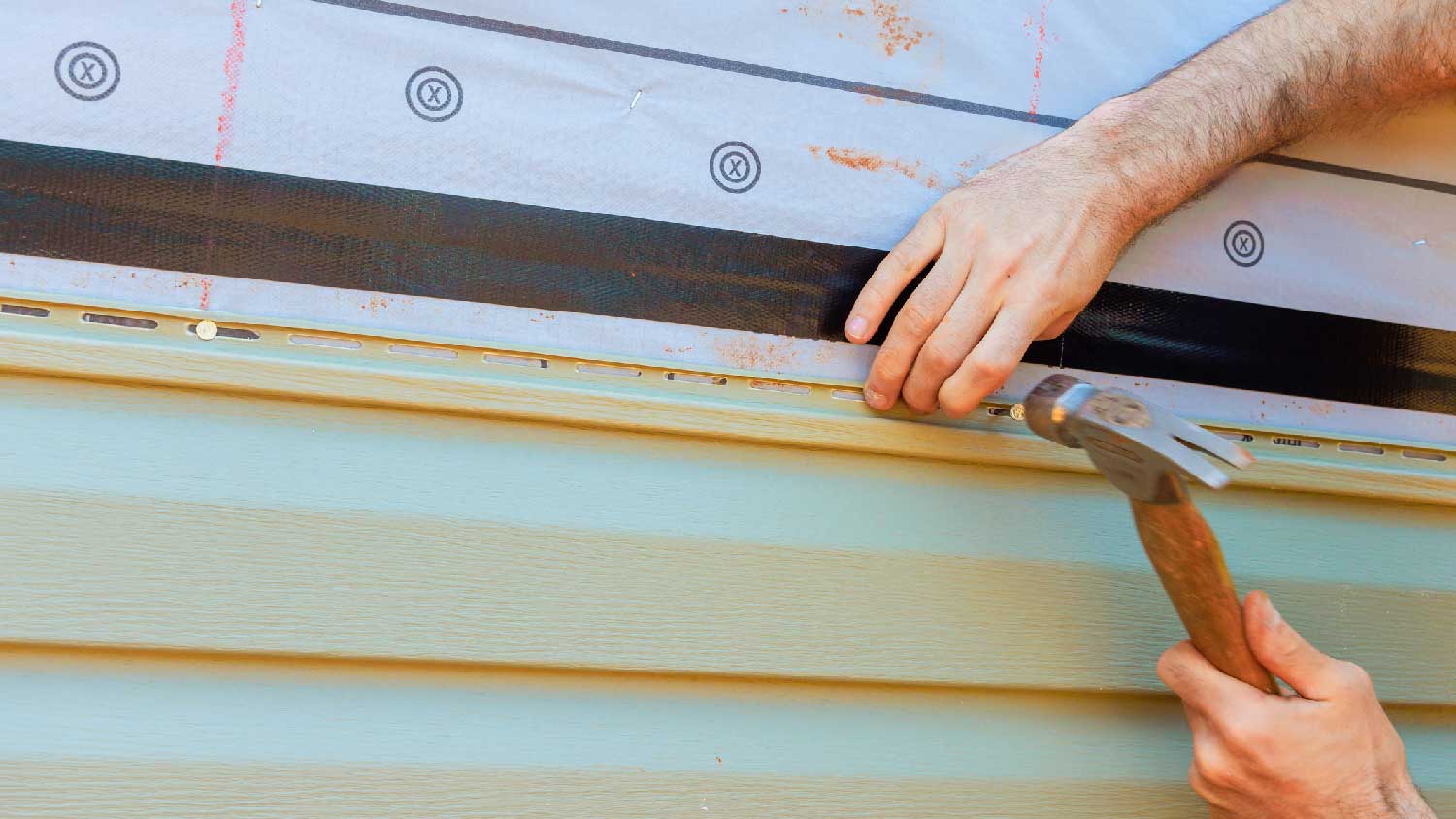 Close-up of a person installing vinyl siding