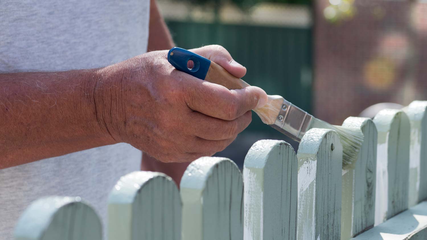 Close-up of a man painting a fence