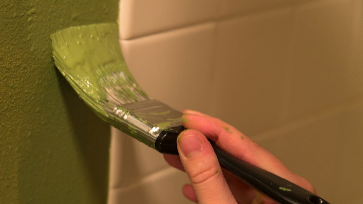 Close-up of painting a bathroom with a brush in a green color