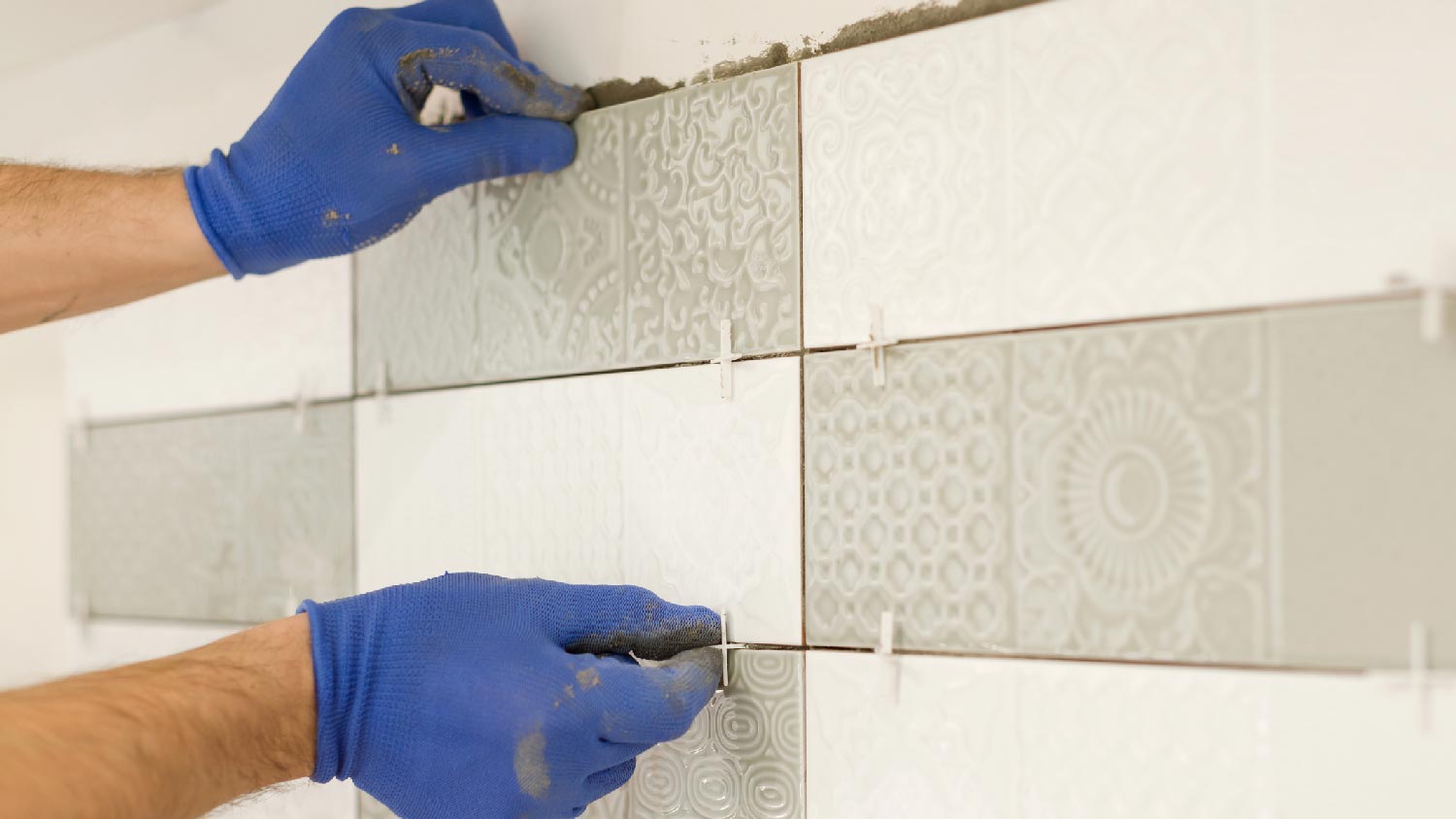 Close-up of a person installing tiles as backsplash