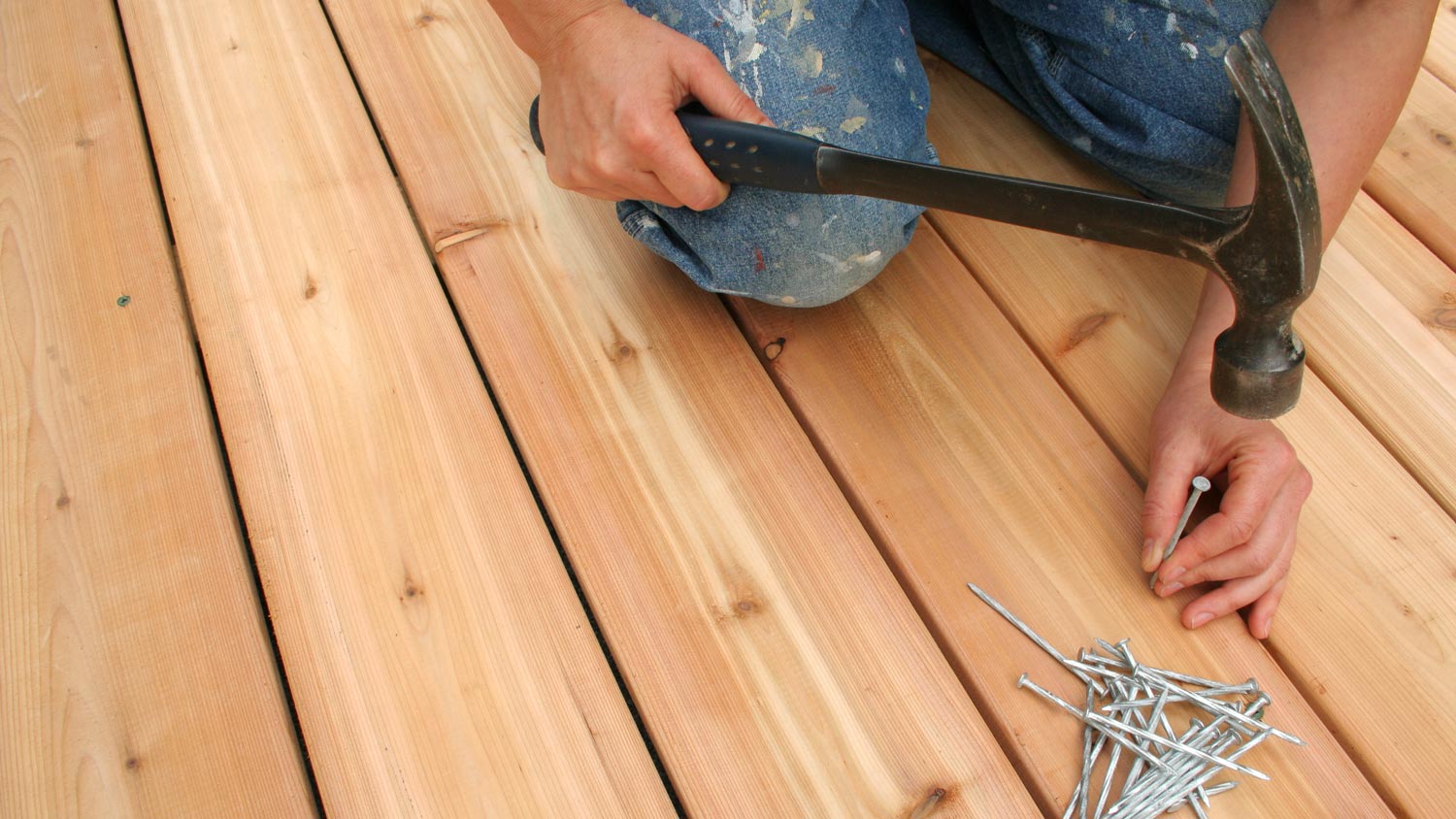 Close-up of a person nailing boards on deck