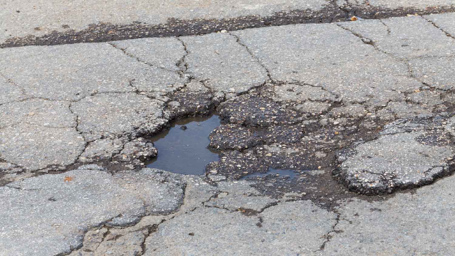 Close-up of a pothole in an asphalt driveway