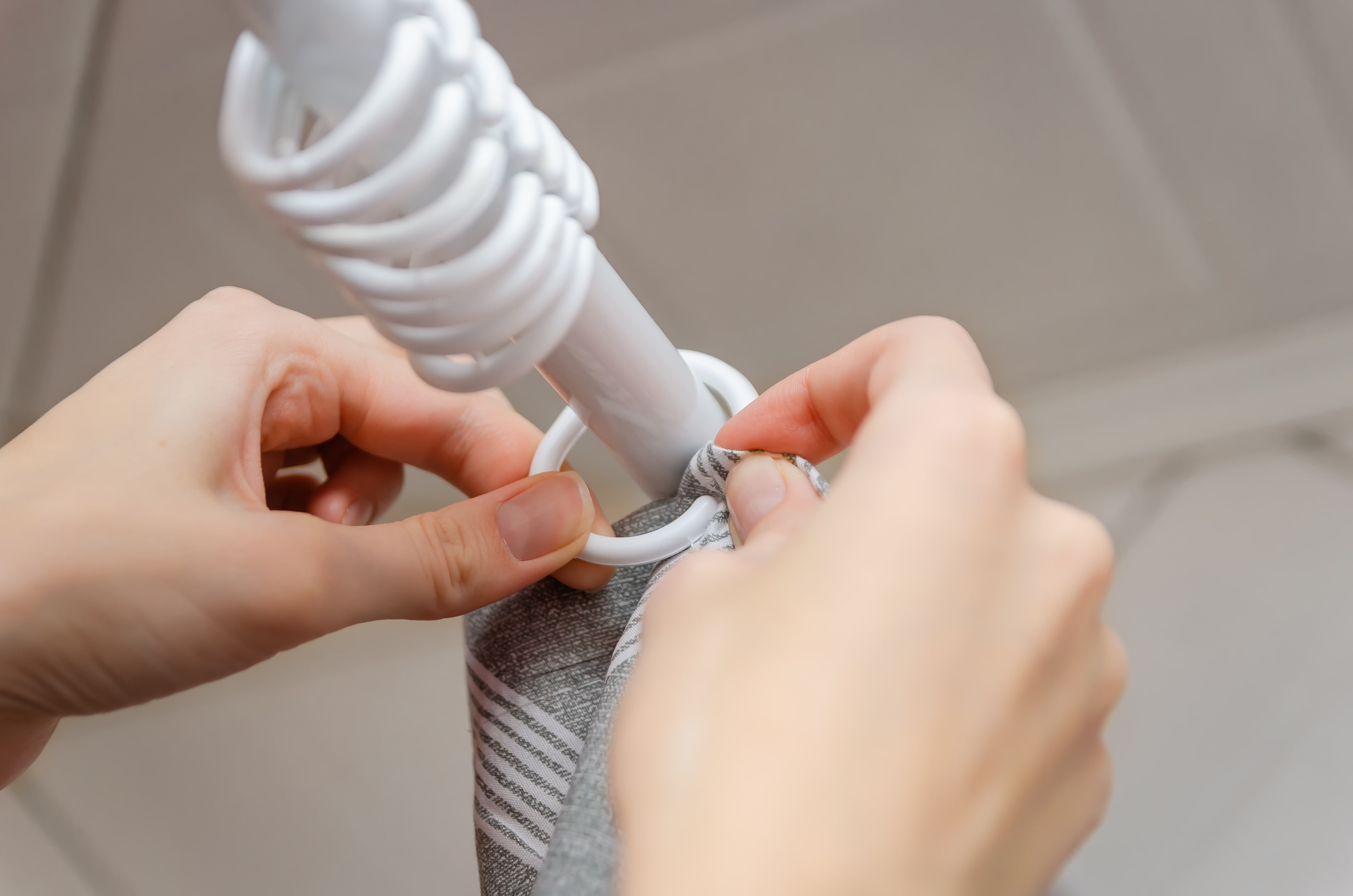 A close up of a woman hanging fabric on curtain rings