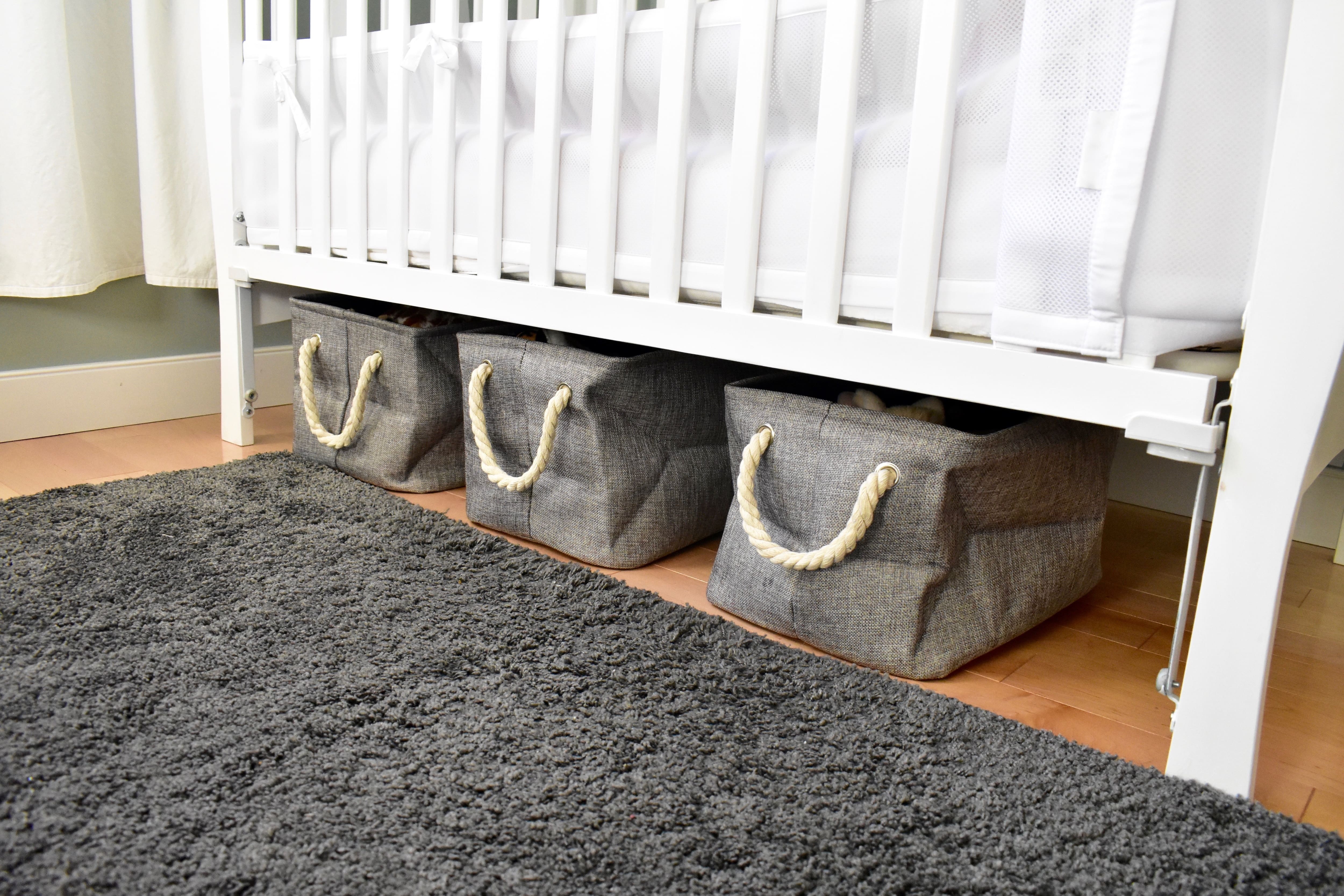 Three gray cloth storage containers under a white crib 