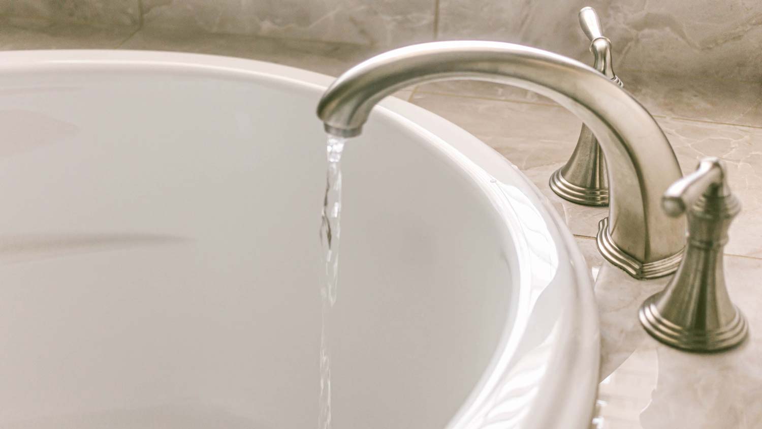 Close-up of running water in a white porcelain bathtub