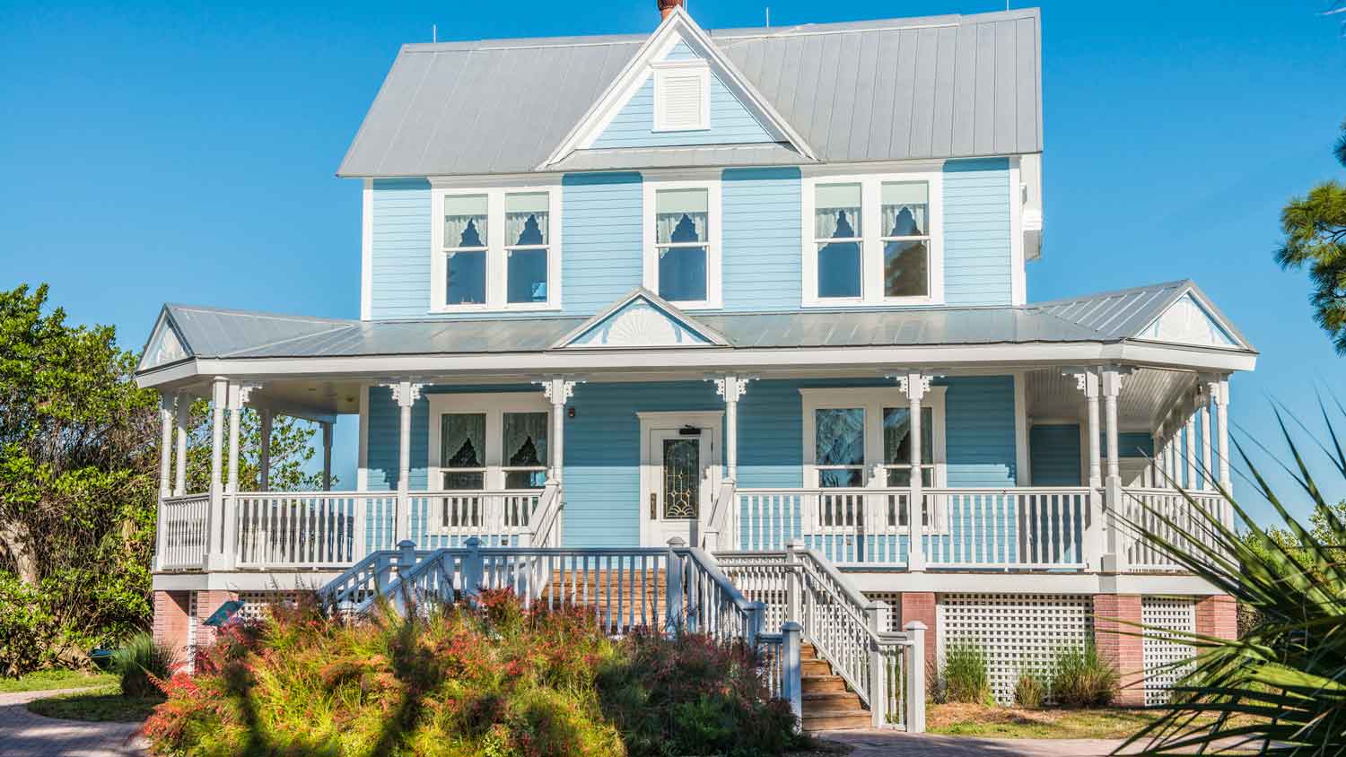 A coastal blue historic home with a metal roof