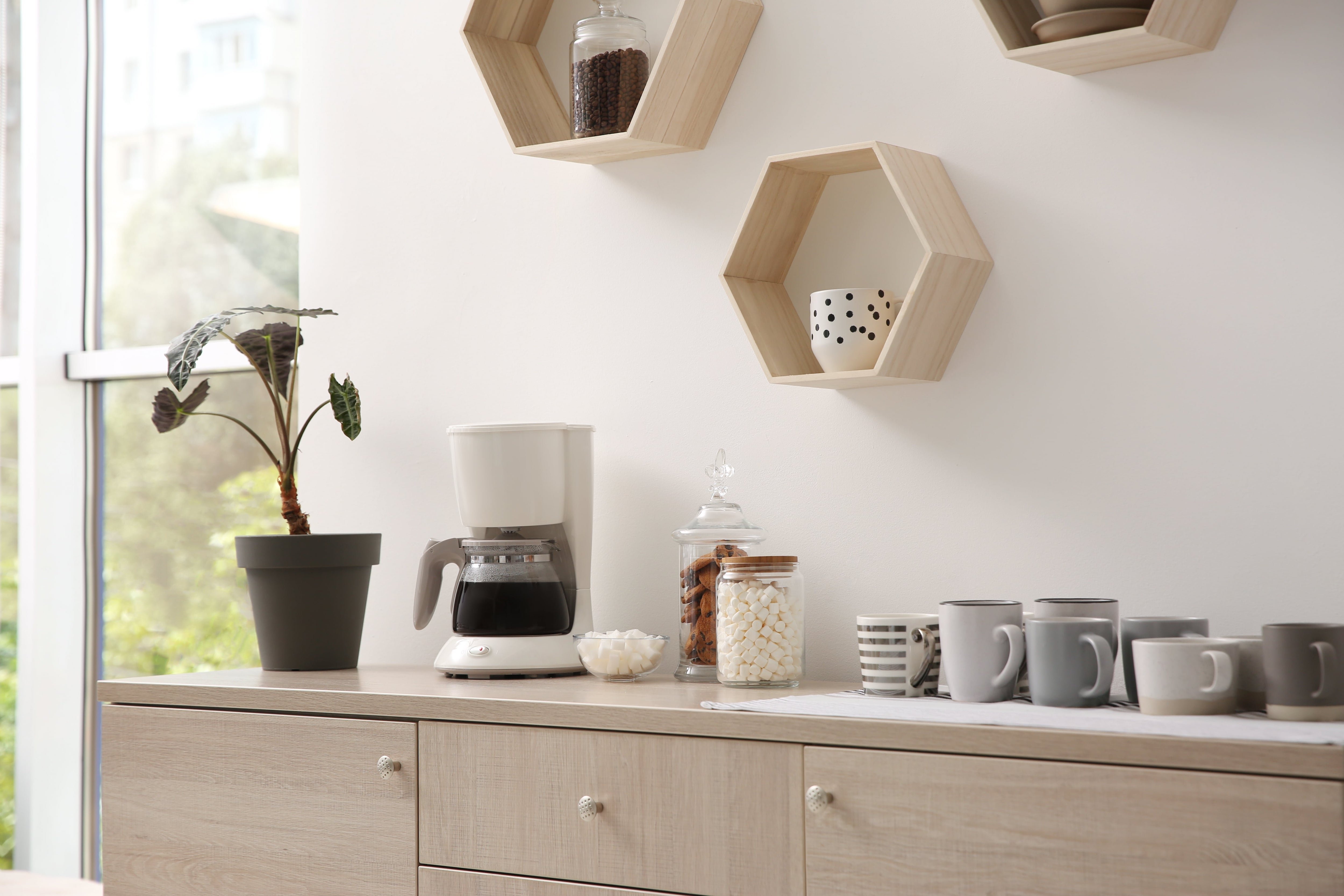 Coffee maker on console table with geometric floating shelves