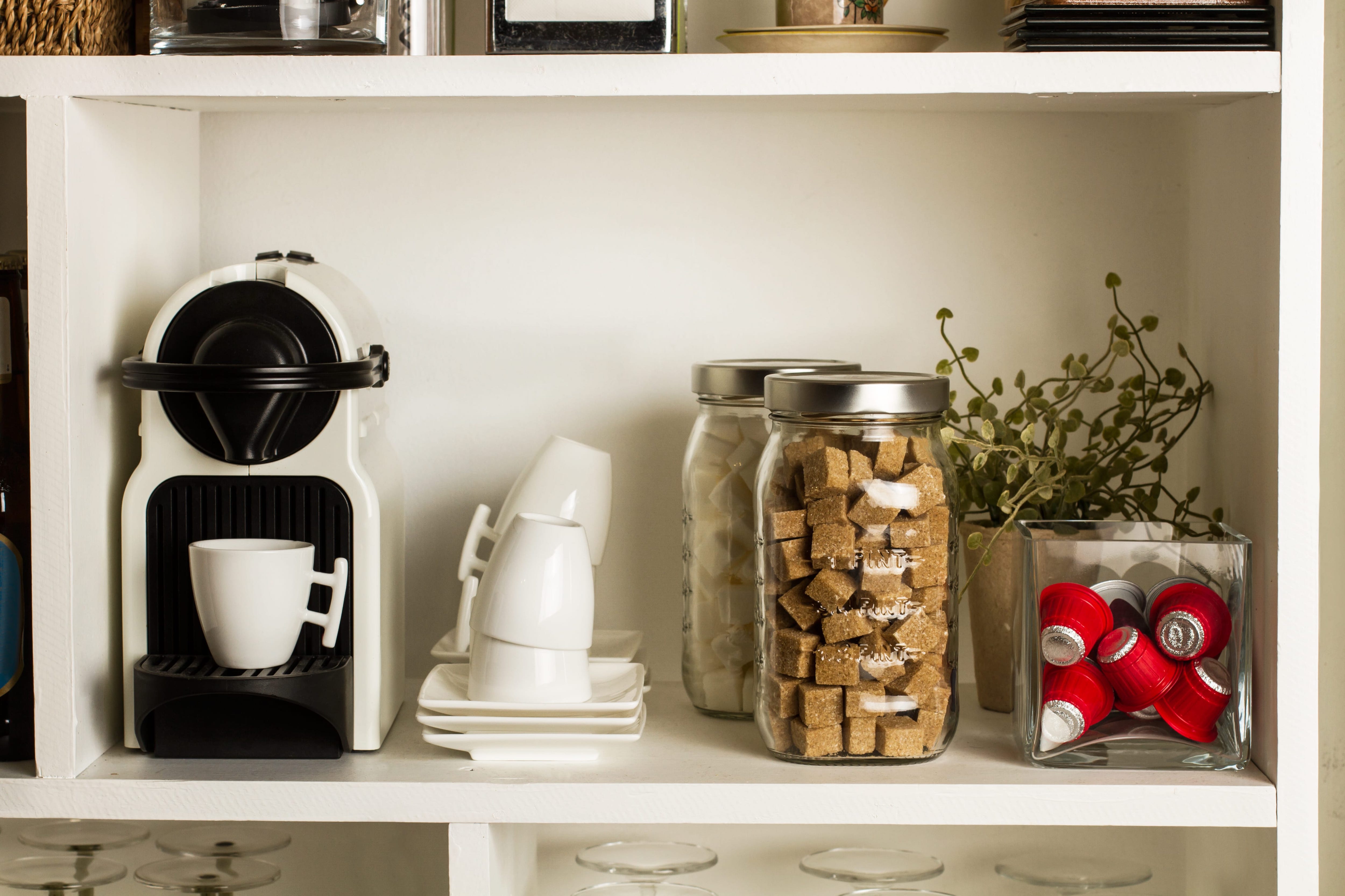 White coffee maker and storage containers on kitchen pantry shelf