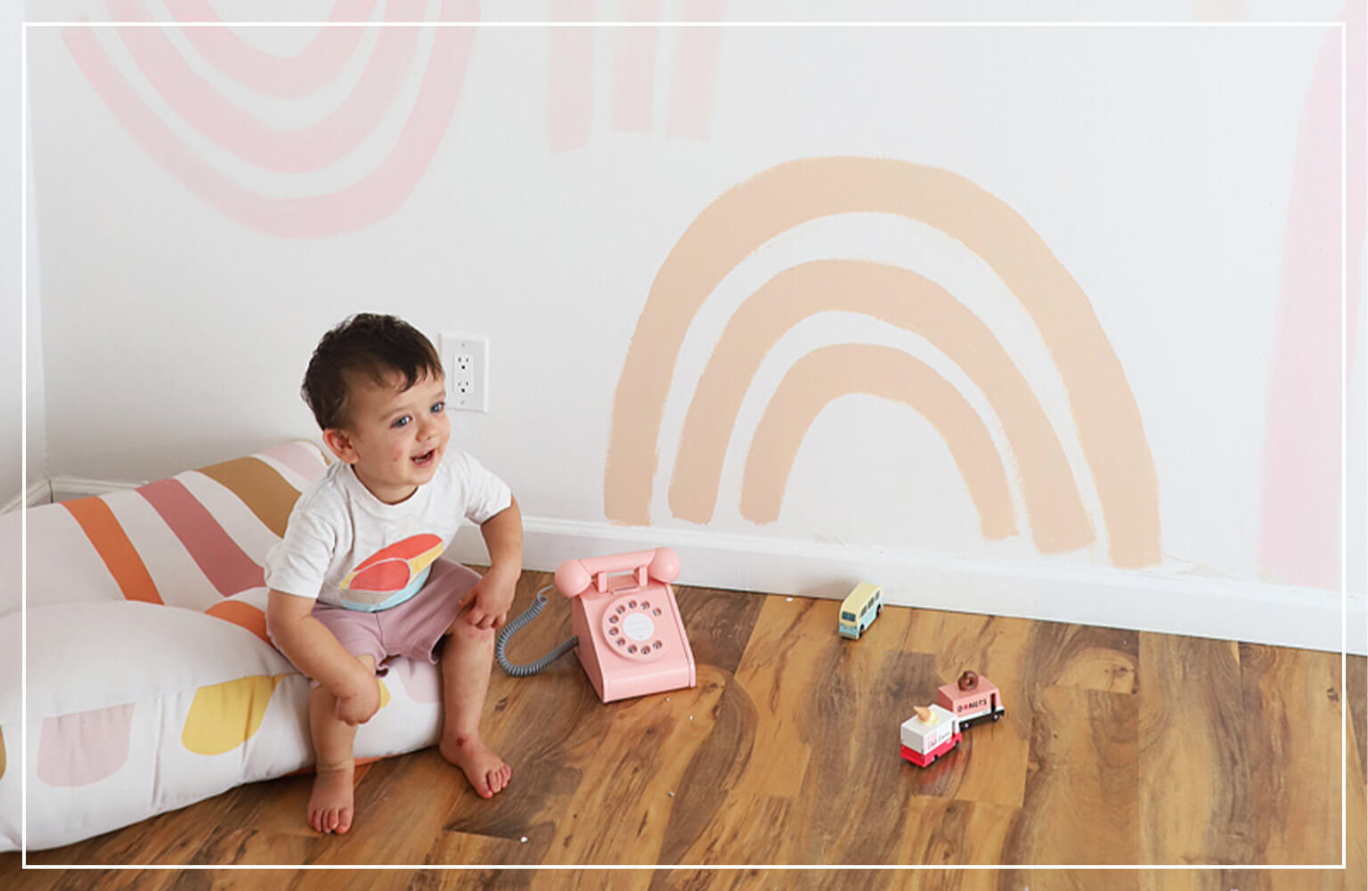 baby sitting on cushion in room with orange arches on wall 