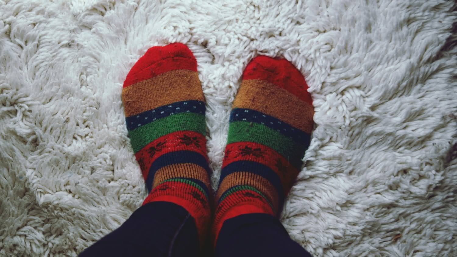 Person wearing colorful socks on a soft carpet