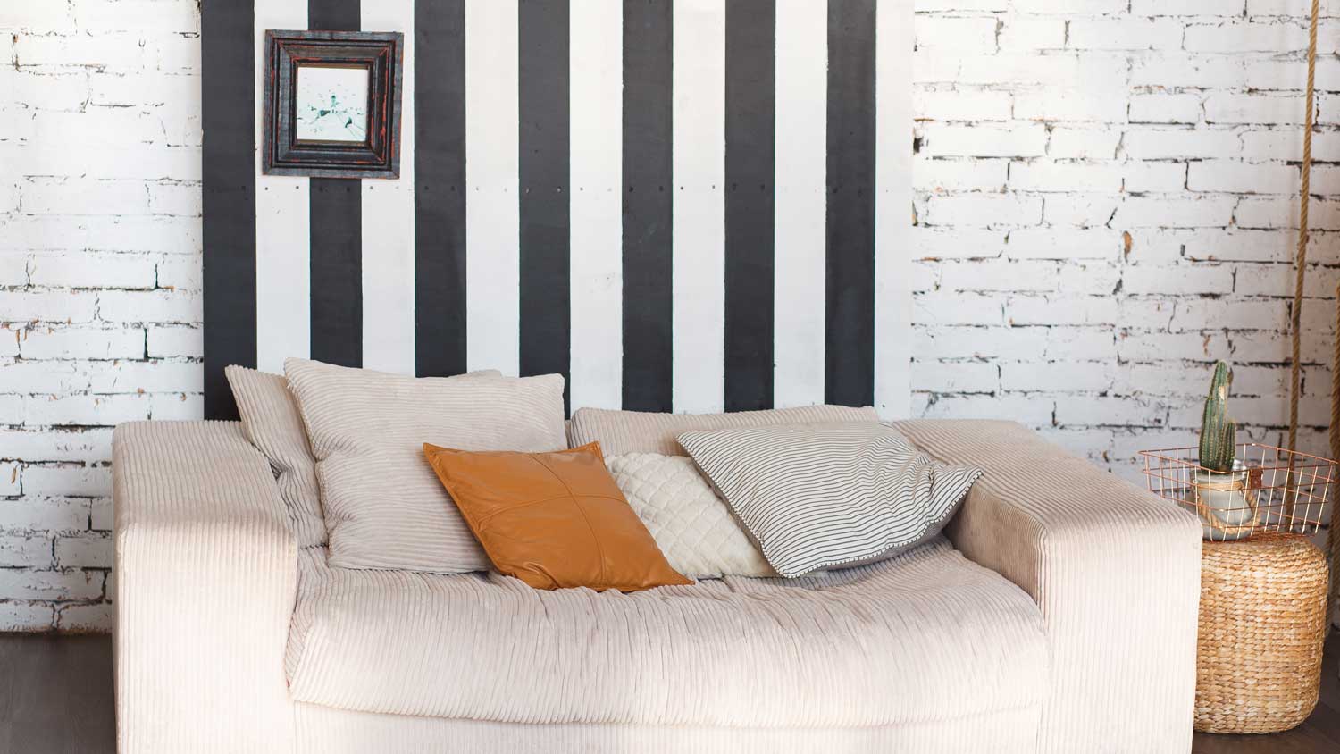 A comfortable sofa with a whitewashed wall on the back