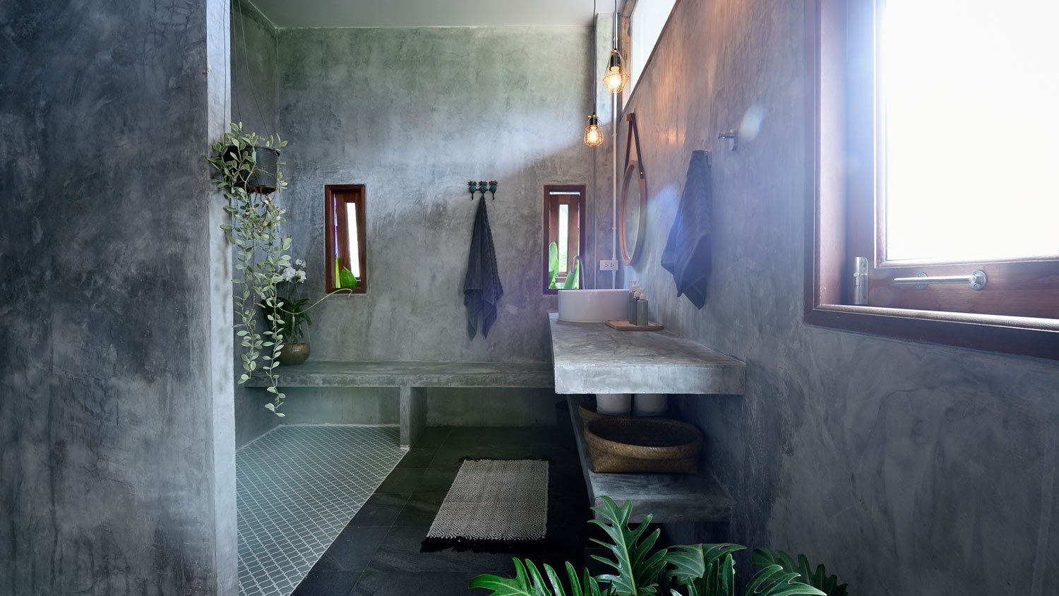 A concrete bathroom with a seat in the shower