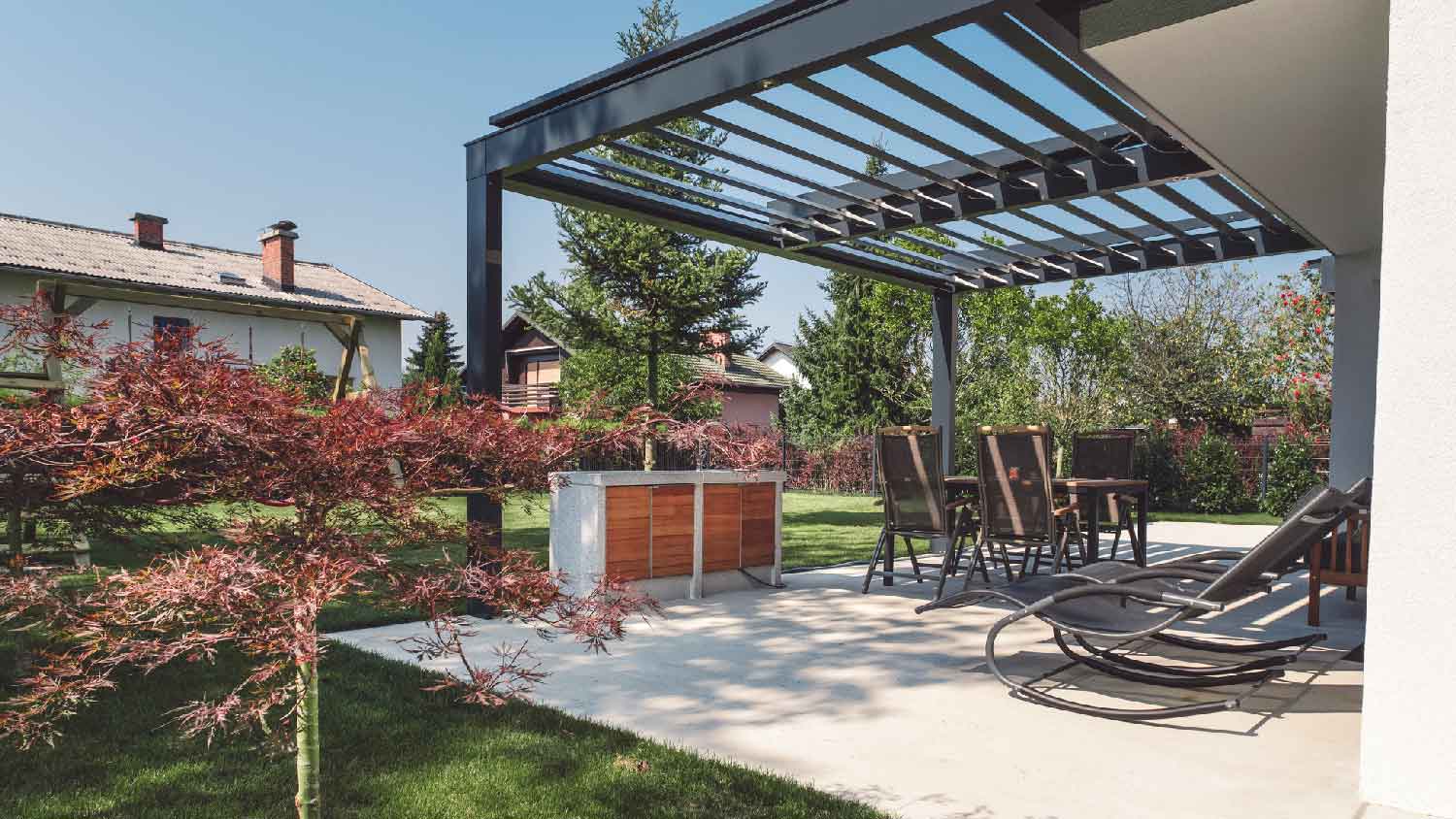 A concrete patio with furniture and a steel pergola 