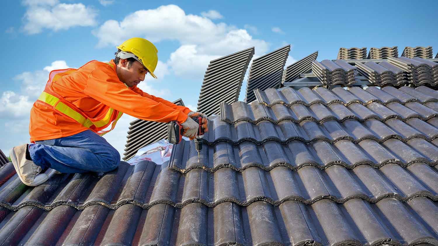 Roofer wearing a helmet installing concrete tiles