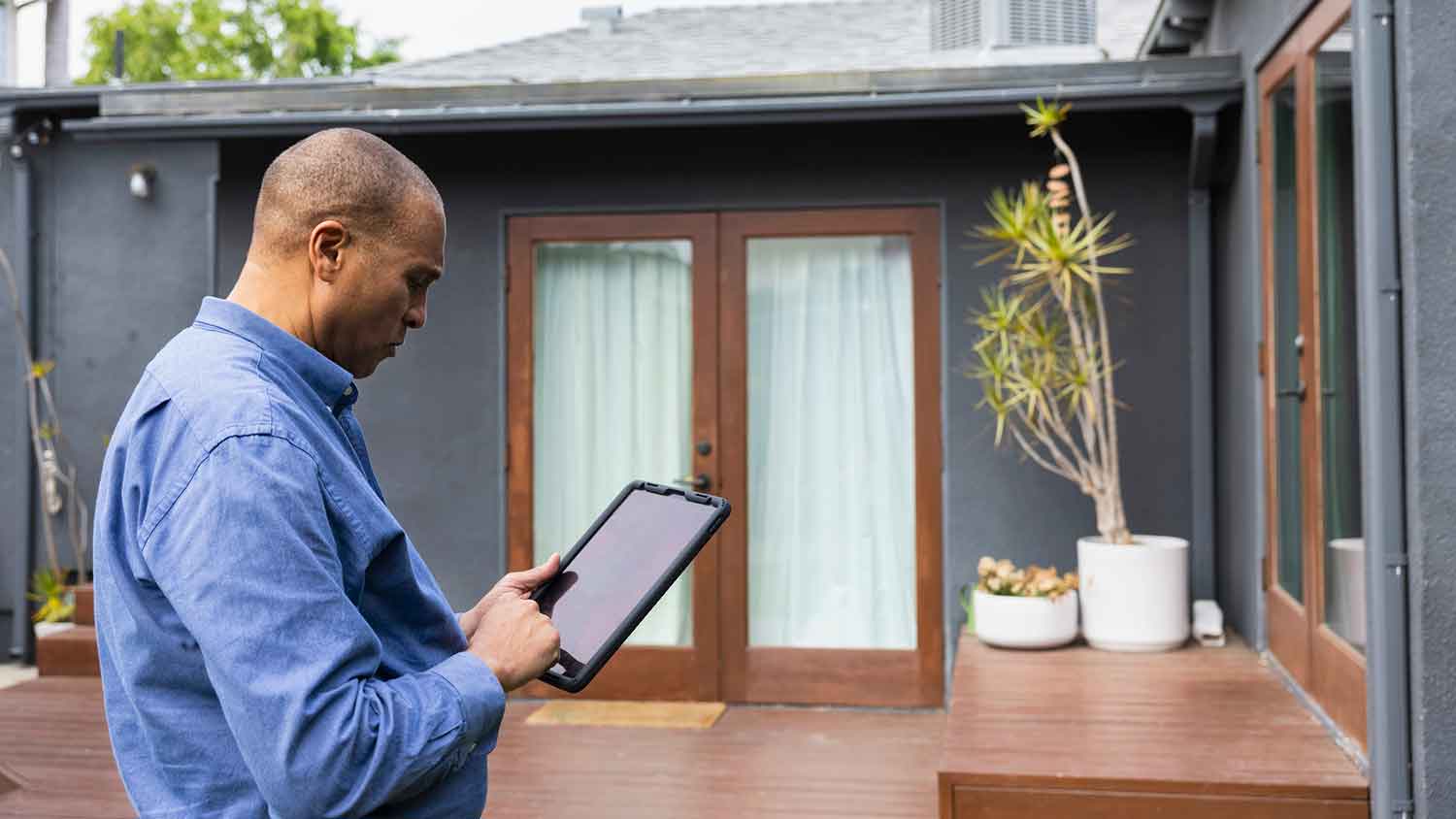 Home inspector holding tablet and checking patio deck