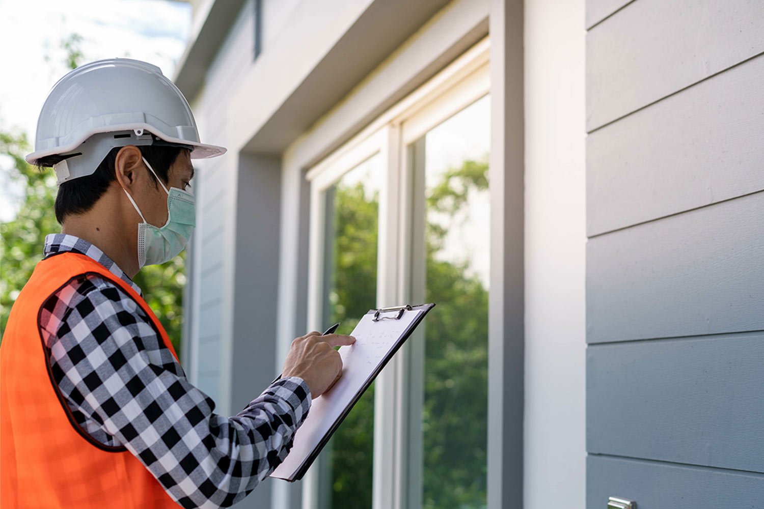 Man taking notes inspecting window of home