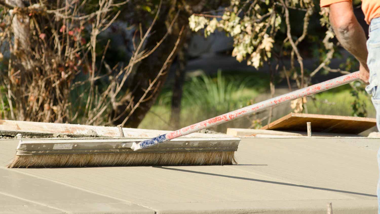 A contractor using a broom to finish concrete