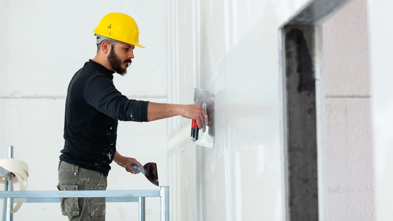 A contractor working on a house’s drywall