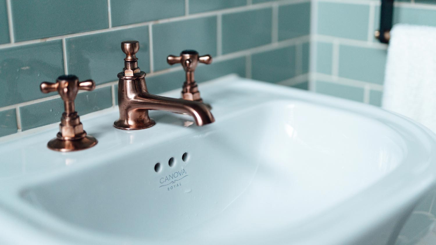 A copper faucet in a beautiful white sink