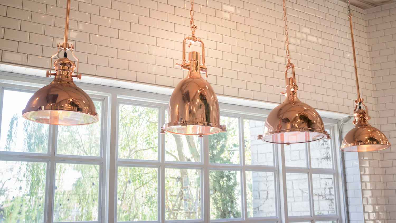 Copper light fixtures hanging from a tall ceiling