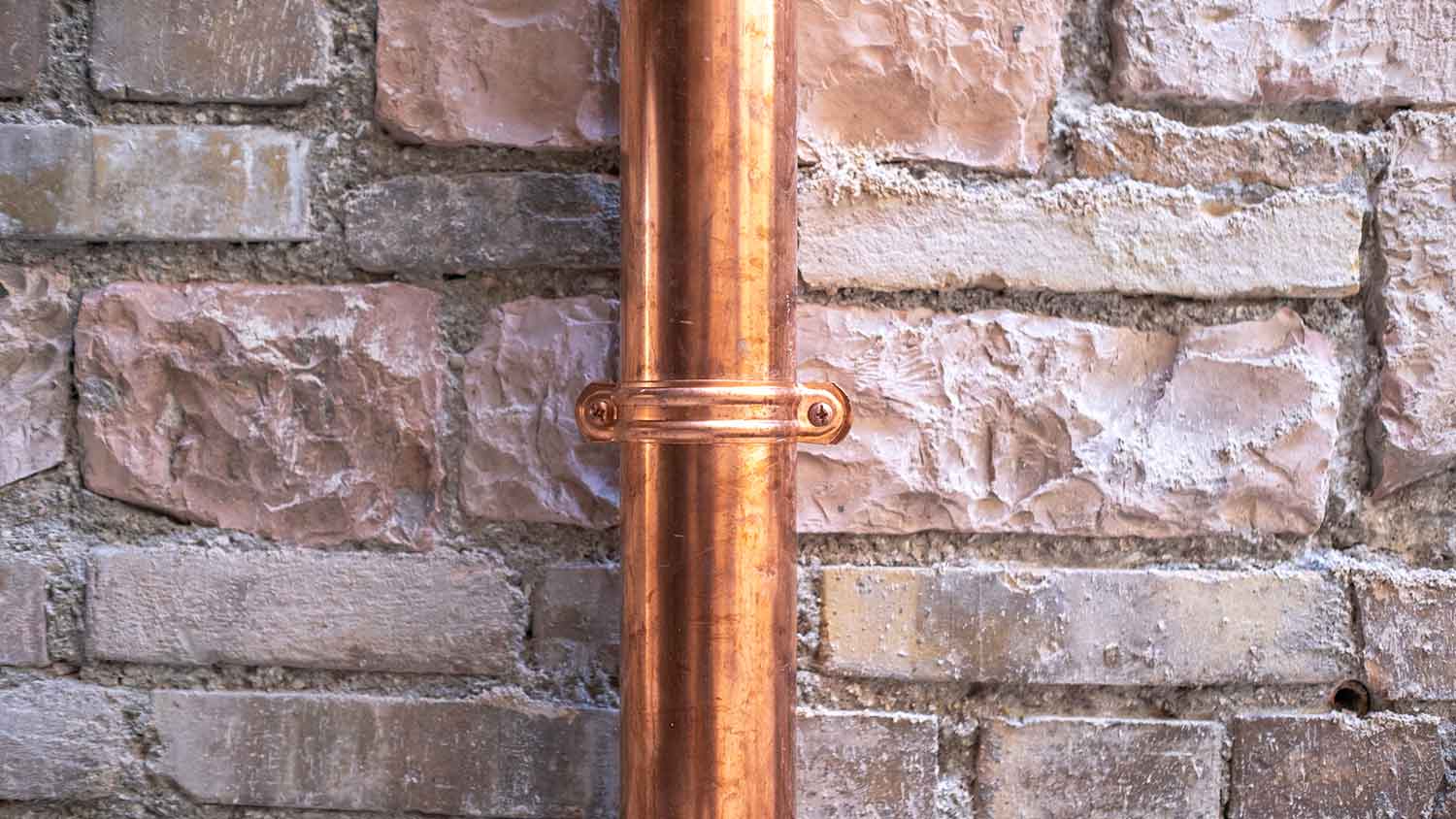 Copper rain gutter mounted on a stone wall