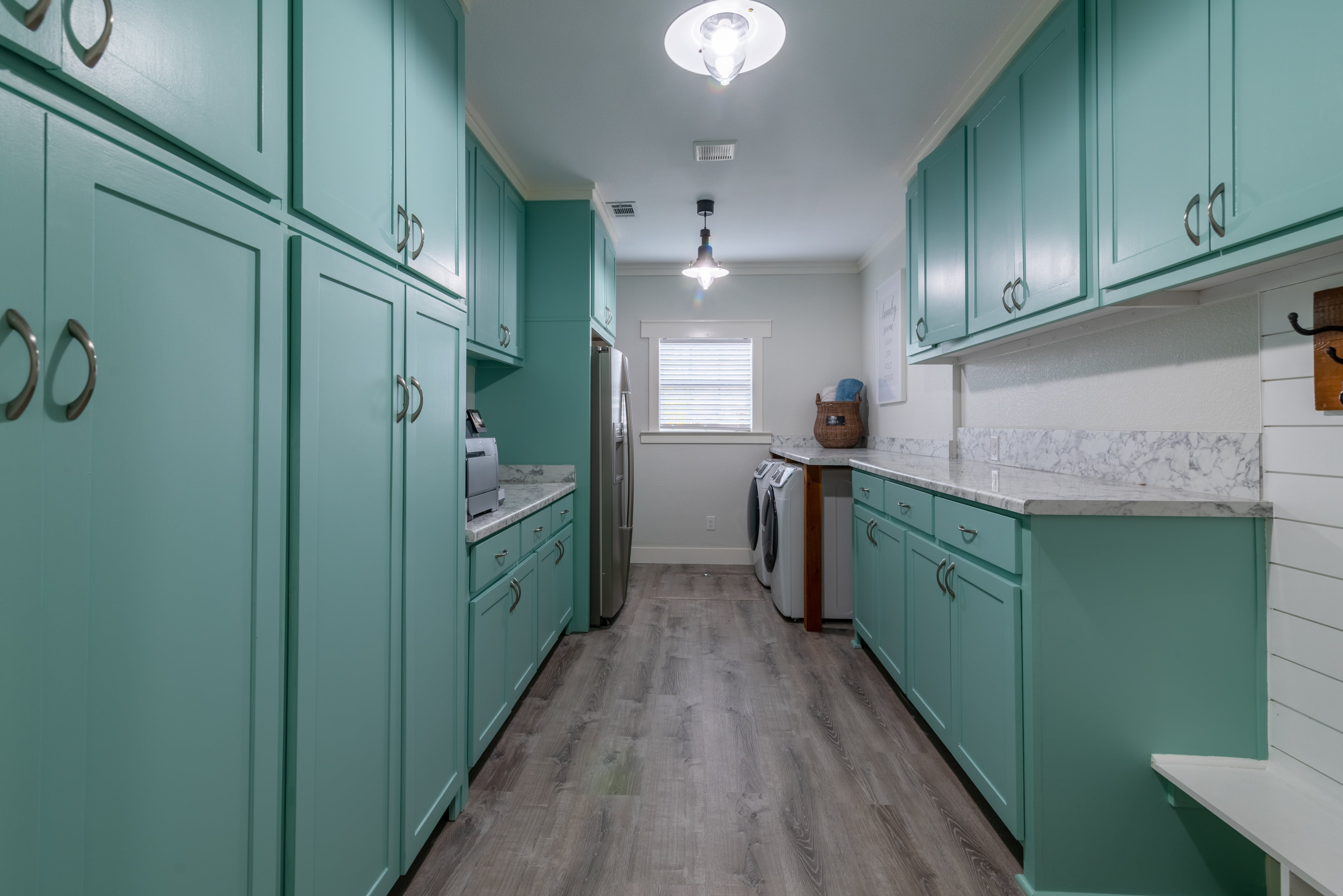 A mudroom with mint green cabinets and marble countertops