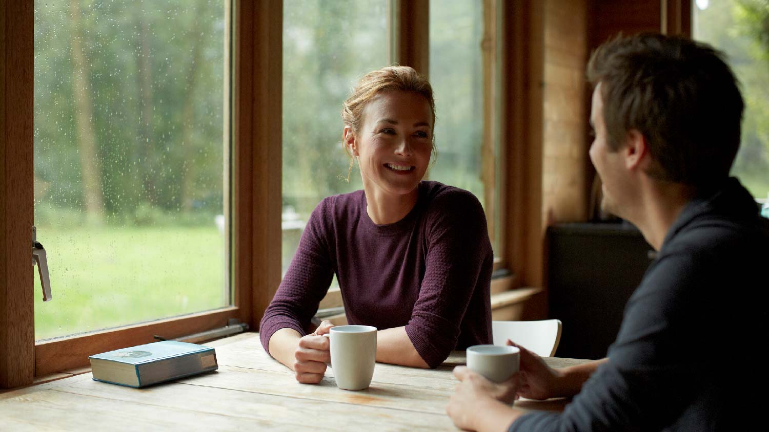 A couple having coffee in a room with wood windows