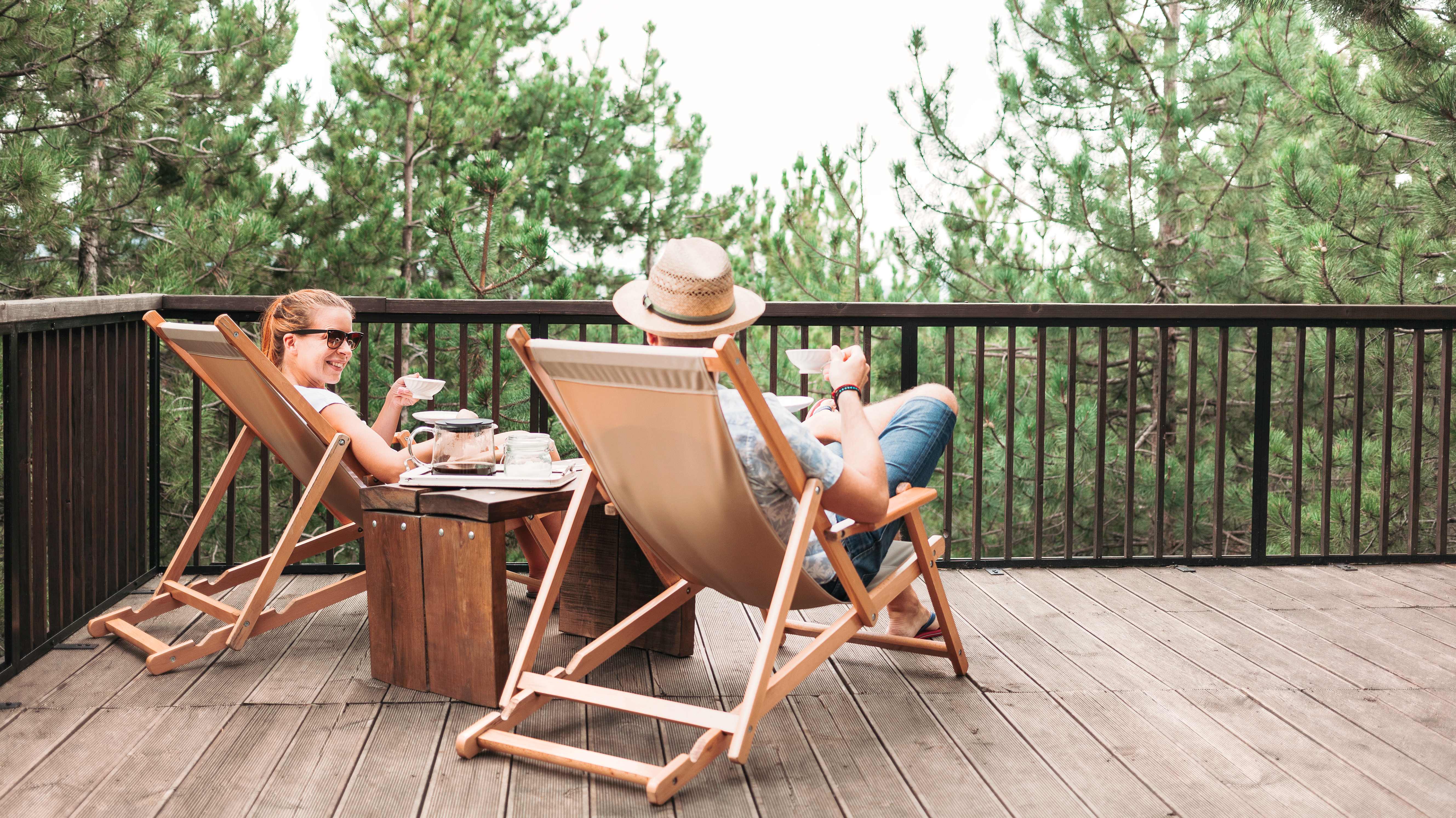 A couple sitting on a wooden deck enjoying coffee